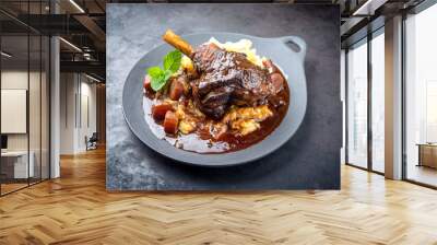 Modern style traditional braised slow cooked lamb shank in red wine sauce with shallots and mashed potatoes offered as top view in a design cast iron plate with copy space Wall mural