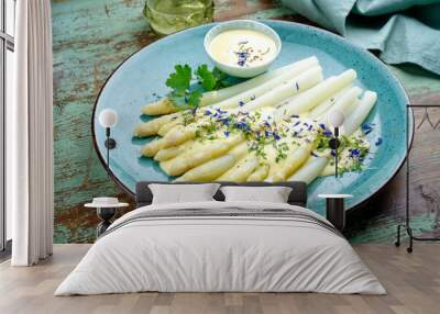 Modern style traditional steamed white asparagus garnished with sauce hollandaise and herbs served as close-up on a design plate Wall mural