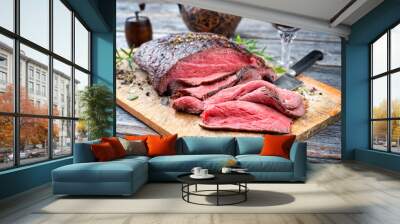 Traditional barbecue dry aged sliced roast beef steak with herbs as closeup on an old cutting board Wall mural