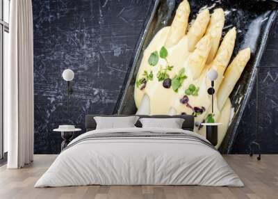 Traditional boiled white asparagus with sauce hollandaise and herbs as top view on a plate with copy space left Wall mural