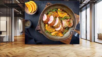 Traditional fried pork filet medaillons in with orange slices and herbs offered as top view in a rustic wrought iron skillet Wall mural