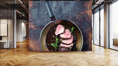 Traditional German venison roast with juniper berry and rosemary in spicy red wine sauce served as top view in a frying pan Wall mural