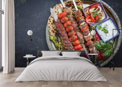 Traditional oriental Adana kebap and shashlik skewer with tomato and flatbread as top view on a plate with copy space left Wall mural