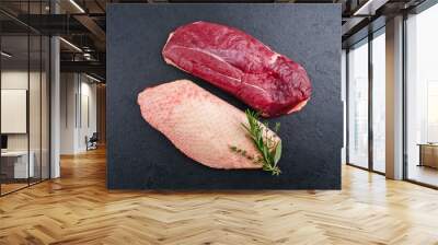 Traditional raw gourmet duck breast filet with skin offered with herbs as top view on a black board Wall mural