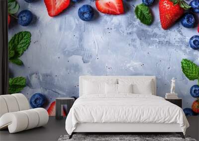 A background in shades of gray with fresh strawberry and blueberry halves and mint leaves neatly arranged in a frame with a designated empty area for text or images. Creative banner. Copyspace image Wall mural