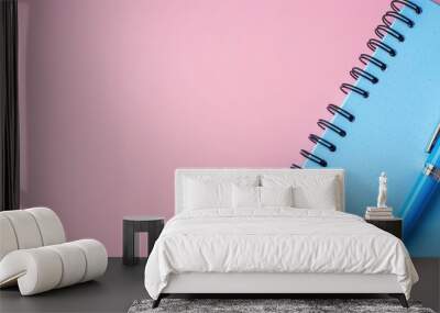 A blue pen and notebook placed on a simple pink backdrop with empty space for an image. Creative banner. Copyspace image Wall mural