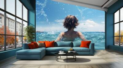 A boy child playing in the sea waves enjoying the summer vacation with water splashes as seen from the back Ideal for a copy space image 167 characters Wall mural