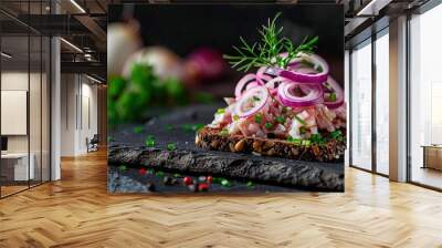 A canape with salted herring onions on dark bread displayed with copy space image on a black background Wall mural