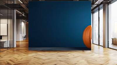 A pumpkin sits on a copy space image of a dark blue Halloween background Wall mural