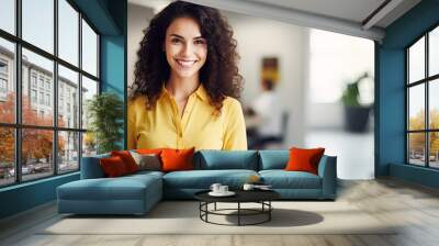 A smiling woman in casual attire holding a pencil and notebook standing in a contemporary office looks at the camera with empty space around her Wall mural