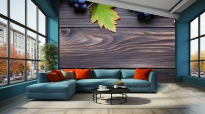 A top down view of blue grapes and vibrant grape leaves on weathered wooden table creating a captivating background for copy space image Wall mural