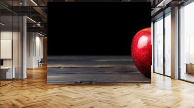 A vibrant red apple resting on a black wooden table with plenty of copy space in the image Wall mural