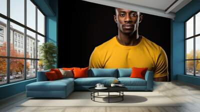 An isolated studio portrait of a young African American man wearing a yellow t shirt posing against a black wall with a sincere expression conveying a lifestyle concept The image includes a mock up w Wall mural