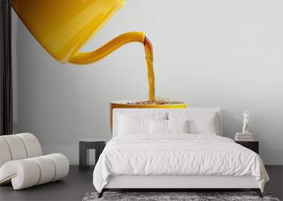 Coffee being poured from a yellow pot into a clear mug set on a white background creating a perfect copy space image Wall mural