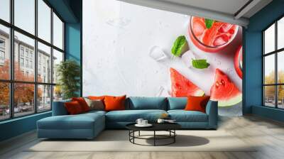 Cold watermelon juice with ice and mint in a glass beside two watermelon slices on a white background creating copy space image Wall mural