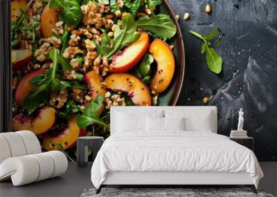 Fresh greens topped with peaches roasted walnuts and pine nuts in a colorful dish with copy space image Wall mural