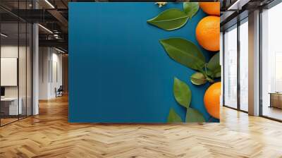 In this blue backdrop a flat lay composition features luscious oranges vibrant leaves and ample space for including text Wall mural