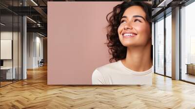 Satisfied Hispanic woman with a positive vibe showcasing an object on copy space Wall mural