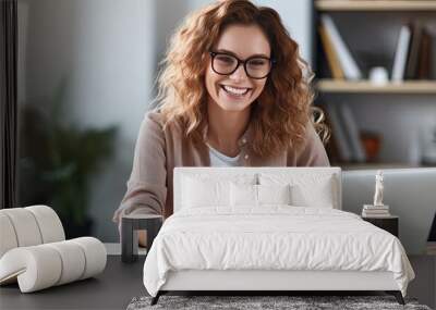 Smiling woman at desk using laptop and notebook studying online at home Wall mural