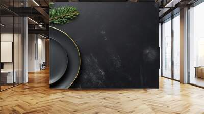 Top view of a Christmas table setting on a black stone background The elegant arrangement includes an empty black ceramic plate a fir tree branch and gold accessories The image has copy space availab Wall mural