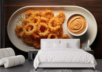 Top view of a plate featuring crispy fried onion rings and a delicious sauce creating a visually appealing copy space image on the table Wall mural