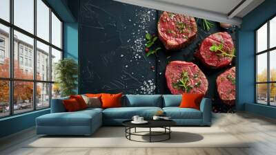 Top view of seasoned filet mignon steaks on black concrete with herbs garlic salt pepper and copy space image available Wall mural