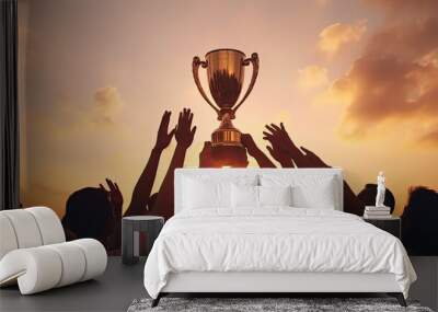 Victorious team triumphs under sunset with trophy and numerous silhouetted hands Wall mural