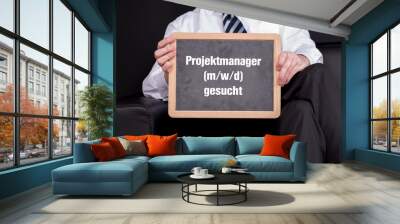 Geschäftsführer mit einer Tafel auf der Projektmanager m/w/d gesucht steht Wall mural