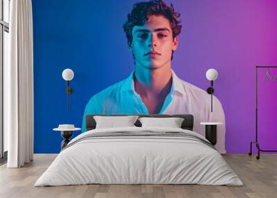 Young man posing confidently in a stylish white shirt with vibrant lighting backdrop Wall mural