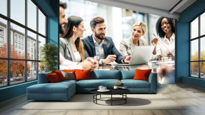 A group of happy, professional businesspeople from diverse backgrounds are sitting together at a meeting table in a modern office space.  Wall mural