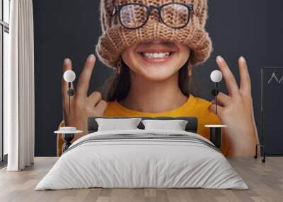 Happy, hide and girl with beanie in studio with glasses for funny, comic or silly joke. Smile, peace sign and woman cover face with knit hat and spectacles for comedy isolated by black background. Wall mural