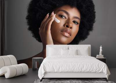 African woman, face cream and studio portrait with afro, skincare or cosmetic by grey background. Girl, model and healthy with natural glow on skin with makeup, clean aesthetic and product for beauty Wall mural