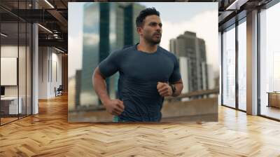 Exercise, running and a sports man in the city for cardio training to improve fitness for a marathon. Wellness, workout or health with a young runner or athlete in an urban town for a speed challenge Wall mural