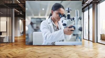 Science, microscope and innovation with a woman in a laboratory for medical research or experiment. Healthcare, medicine and a young indian engineer working in a lab for pharmaceutical development Wall mural