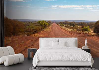 Unpaved road from Kings Canyon to Alice Springs near the Ginty's Lookout. Endless vast landscape with barren vegetation on thousands of kilometers in central Australia. Red sand road Wall mural