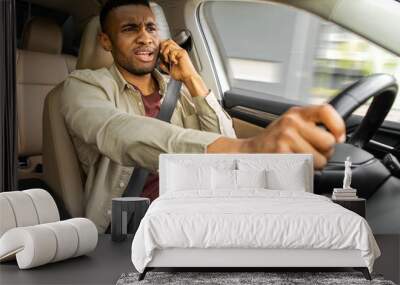  Angry african young man fighting on the phone while driving a car, careless driver using his mobile phone, view right inside the car Wall mural