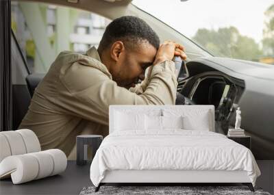 African american man sleeping in a car, resting head on wheel Wall mural