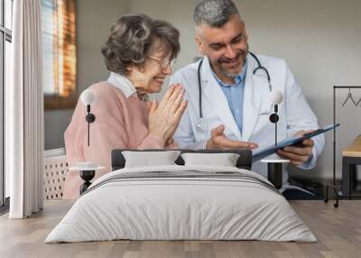 Caring man doctor talking and consult satisfied elderly female patient, doc doing regular checkup consultation to senior woman client Wall mural