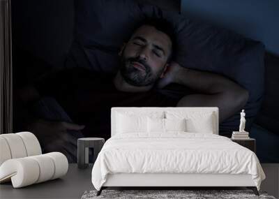 Top view of a handsome bearded man sleeping comfortably at night on the bed in his bedroom. Wall mural