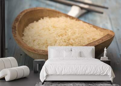 Rice in a wooden plate on a blue background.  Wall mural