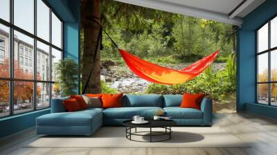 Orange hammock hanging tied to two trees at the nature. Wall mural