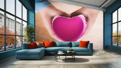 Right hand holds heart with blue sky background  Wall mural