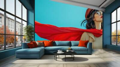 Confident looking mighty powerful young adult person wearing superhero costume on blue background. Portrait of happy brave woman with superpowers wearing red hero cape while standing with arms Wall mural