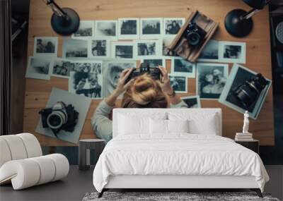 Top view of young woman photographer working in studio. Female photographer checking image prints. Wall mural