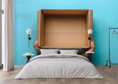 A person holding out an empty cardboard box against blue background, top view.
 Wall mural