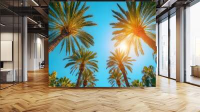 Palm tree avenue under clear blue sky, vibrant green palm fronds, tropical paradise, sun flare through leaves, cloudless azure sky, summer vacation atmosphere, lush oasis, exotic landscape. Wall mural