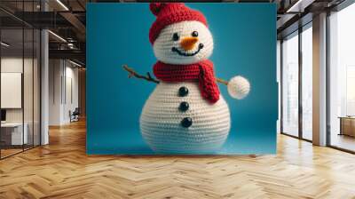 A crochet snowman with.a snowball, on a blue studio background - close up of a cute knitted christmas holiday kids toy or craft idea Wall mural