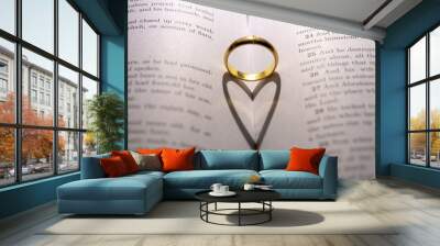 A wedding Ring on the bible with shadow of heart shape on the page Wall mural