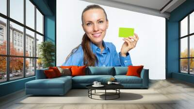 Beautiful business woman is smiling and holding a card in her hand. Wall mural