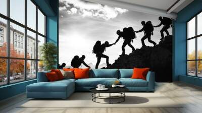 A group of people are climbing a mountain together. The image is in black and white and the people are silhouetted against the sky. Scene is one of teamwork Wall mural